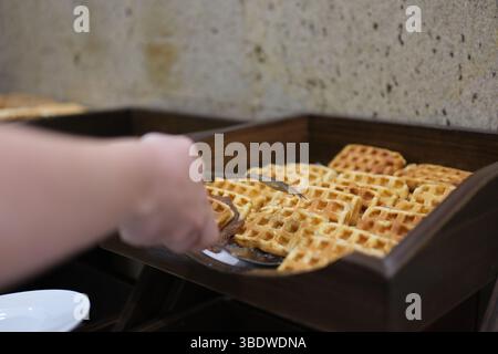 Waffle belgi su un piatto con abbondante guarnizione di cioccolato liquido. Primo piano, dolly shot che cattura la deliziosa consistenza e il dolce momento della colazione. Foto Stock