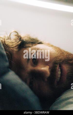Ritratto di un uomo che si rilassa sul letto a casa, da vicino Foto Stock