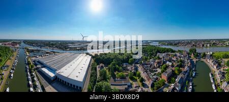 Klein-Willebroek, Willebroek, Anversa, Belgio, 13 maggio, 2025, goditi una vista panoramica mozzafiato che mostra un vivace paesaggio fluviale adornato da numerose turbine eoliche Foto Stock