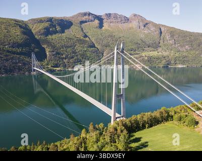 Norvegia, Ponte Hardanger: Vista droni di una meraviglia dell'ingegneria moderna che si innalza su un pittoresco fiordo tra le montagne. Foto Stock