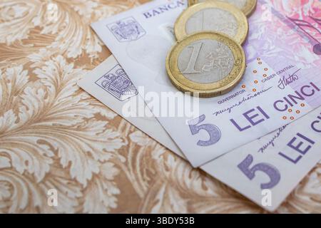 Una moneta in euro su banconote di plastica da 5 lei o ron , concetto di devalorizzazione del cambio, primo piano focale morbido Foto Stock