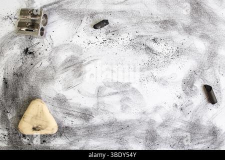 Polvere nera e macchie sulla carta bianca accanto a una gomma e a un affilatore Foto Stock