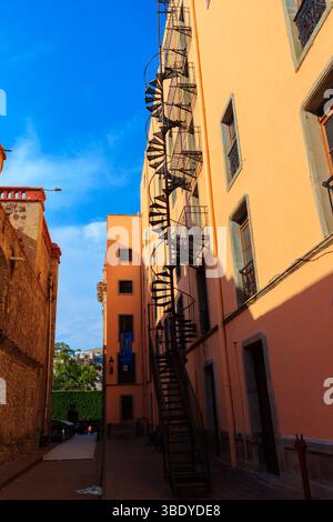Guanajuato City, Messico - 30 maggio 2016: Una scala a chiocciola sale sul lato di un edificio color pesca, offrendo un percorso alternativo. Foto Stock