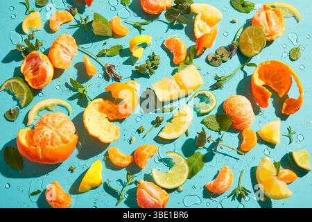 Fette di agrumi, bucce ed erbe sparsi su sfondo blu Foto Stock