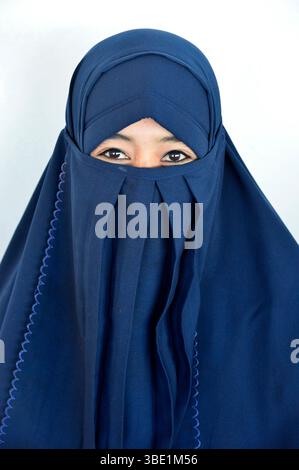 Una giovane donna che indossa un niqab blu a Sumbawa, Indonesia, Sud Est Asiatico. Foto Stock