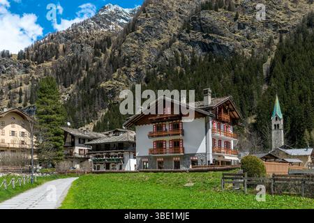 Una vista pittoresca dell'affascinante villaggio di Gressoney-Saint-Jean con tradizionali edifici in legno e pietra sullo sfondo di una montagna in Italia. Foto Stock