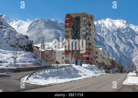 Città nella parte montuosa del paese. Edificio a più piani decorato con mosaici di epoca sovietica. Tyrnyauz (Тырныауз), Russia. Foto Stock