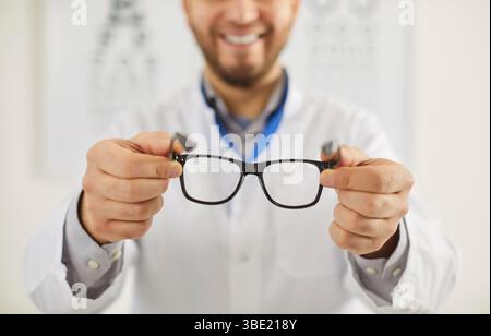 Uomo oftalmologo che tiene occhiali con lenti correttive, prendendosi cura della vostra salute degli occhi Foto Stock