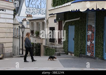 Woman Walking Small Dog Past Green Facade and Street Art a Montmartre, Parigi Foto Stock