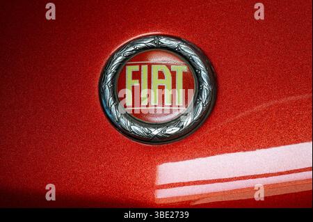 Primo piano di un logo Fiat vintage, che mostra lo storico emblema del marchio su una classica auto rossa Foto Stock