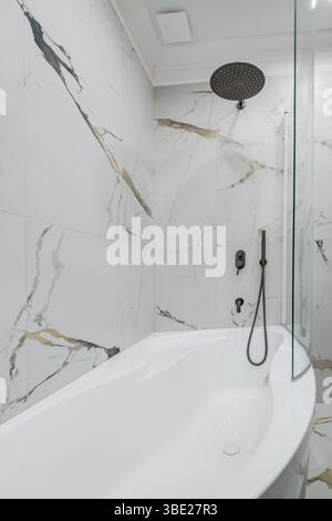Bagno contemporaneo con lavandino bianco su ripiano in legno, doccia in vetro con gocce di pioggia e pareti piastrellate grigie. Foto Stock