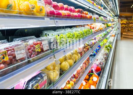 Frutta del supermercato sezione refrigerata con file di frutta fresca confezionata, tra cui uva, mele, mango e pere, in mostra freschezza e convenienza Foto Stock