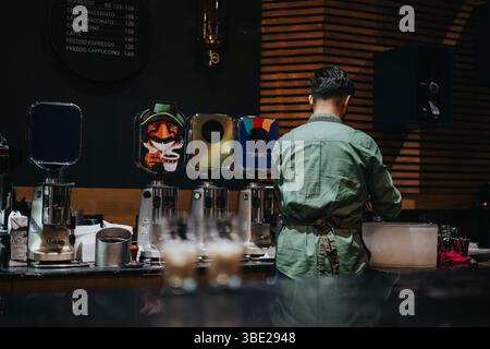 Barista che prepara bevande in un accogliente ambiente di caffetteria Foto Stock