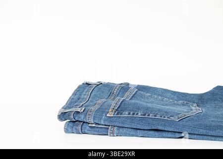 Jeans blu piegati su sfondo bianco, abbigliamento da uomo essenziale per il catalogo o il negozio online Foto Stock