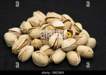 Pistacchio arrostito in guscio su sfondo nero (Antep Fistigi), arachidi arrostite (Pistacchio) Foto Stock