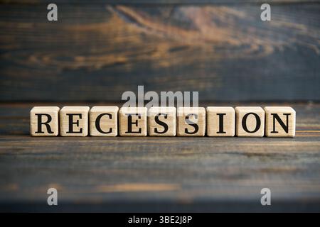 Blocchi di legno con lettere che formano la parola RECESSIONE, disposti su una superficie rustica di legno. Foto Stock