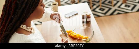 Una giovane donna afroamericana prepara sapientemente un'insalata fresca nella sua accogliente cucina, lo striscione Foto Stock