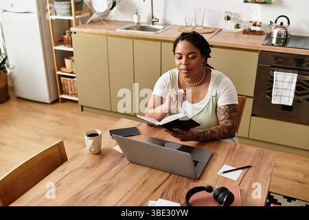 Una giovane donna si impegna a lavorare da casa, rivedendo appunti e concentrandosi sul proprio notebook. Foto Stock