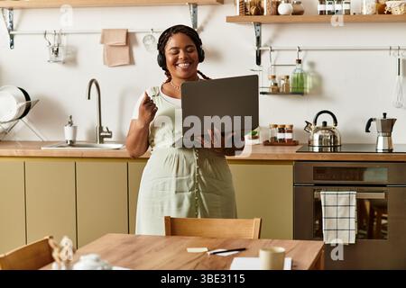 Una giovane donna afroamericana si impegna a lavorare come freelance a casa, irradiando gioia e concentrazione. Foto Stock