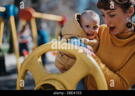 Mamma e bambino si divertono insieme in un parco giochi all'aperto in una giornata di sole Foto Stock