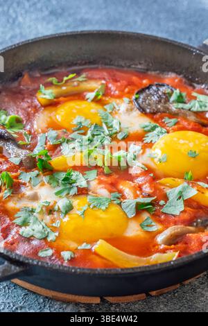 Uova sospese a base di pomodoro speziato con funghi, peperoni ed erbe fresche Foto Stock