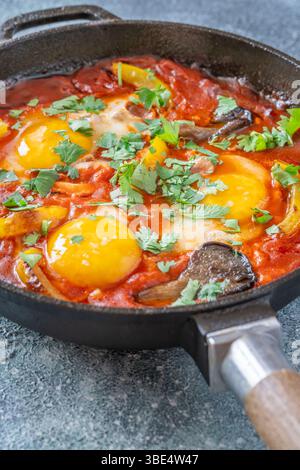 Uova sospese a base di pomodoro speziato con funghi, peperoni ed erbe fresche Foto Stock