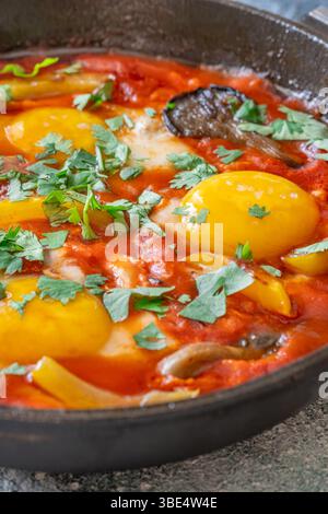 Uova sospese a base di pomodoro speziato con funghi, peperoni ed erbe fresche Foto Stock