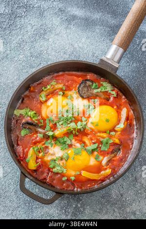 Uova sospese a base di pomodoro speziato con funghi, peperoni ed erbe fresche Foto Stock