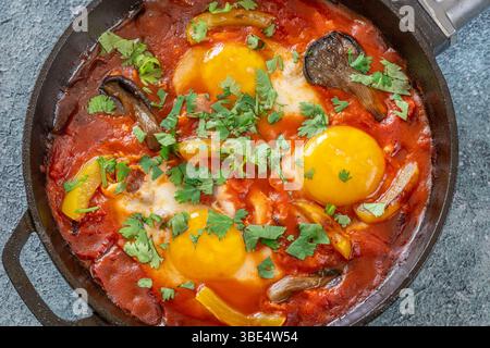 Uova sospese a base di pomodoro speziato con funghi, peperoni ed erbe fresche Foto Stock