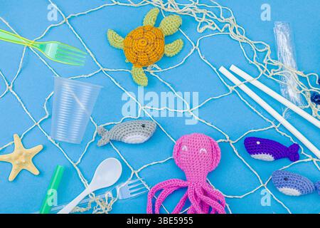 World Oceans Day, water pollution awareness, and environmental education visuals. Handmade crochet marine animals trapped in disposable plastic items Foto Stock