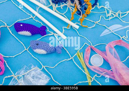 World Oceans Day, water pollution awareness, and environmental education visuals. Handmade crochet marine animals trapped in disposable plastic items Foto Stock