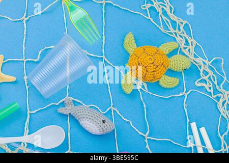 World Oceans Day, water pollution awareness, and environmental education visuals. Handmade crochet marine animals trapped in disposable plastic items Foto Stock