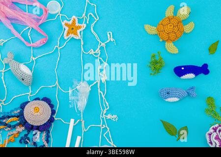 World Oceans Day, water pollution awareness, and environmental education visuals. Handmade crochet marine animals trapped in disposable plastic items Foto Stock