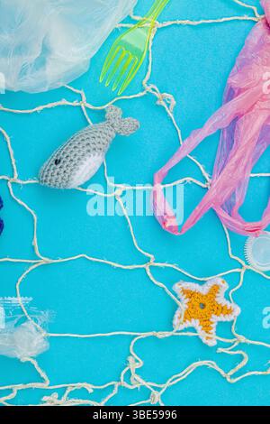 World Oceans Day, water pollution awareness, and environmental education visuals. Handmade crochet marine animals trapped in disposable plastic items Foto Stock