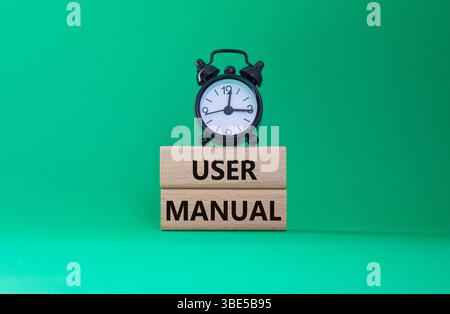 Simbolo del manuale d'uso. Parole concettuali Manuale d'uso su blocchi di legno. Splendido sfondo verde con sveglia. Informazioni sul manuale d'uso e sul manuale d'uso. Copia sp Foto Stock