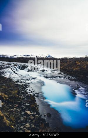 La splendida cascata di Bruarfoss, conosciuta per le sue acque cristalline e turchesi, che scorre sopra scure rocce vulcaniche circondate dalle aspre terre dell'Islanda Foto Stock