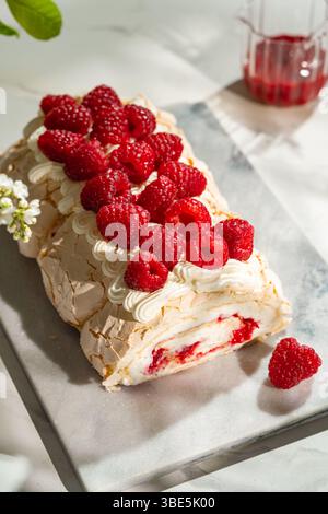 Deliziati con una deliziosa meringa di lamponi, ripiena di panna montata e condita con lamponi freschi. Questo delizioso dessert è perfetto per Foto Stock