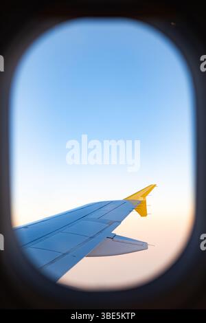 Scattata dalla finestra di un aereo, questa immagine rivela una vista mozzafiato del cielo e dell'ala sopra le nuvole, offrendo un senso di libertà e di avventura Foto Stock