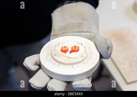 Primo piano della mano dei guanti di un artigiano che regge intricati pezzi di vetro di Burano e Murano provenienti da Venezia. Questi vivaci vetri realizzati a mano sono caratterizzati da tr Foto Stock