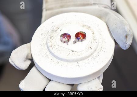 Primo piano della mano dei guanti di un artigiano che regge intricati pezzi di vetro di Burano e Murano provenienti da Venezia. Questi vivaci vetri realizzati a mano sono caratterizzati da tr Foto Stock