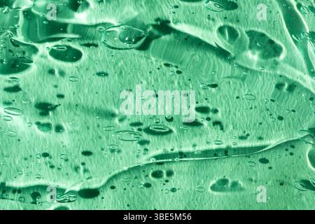 Un accattivante primo piano di una texture di gel verde, che mostra intricate bolle e motivi fluidi. L'immagine acquisisce la superficie liscia e lucida, embo Foto Stock