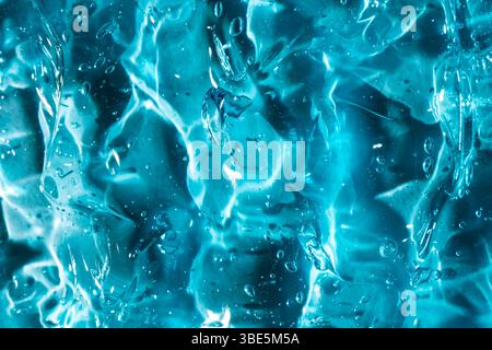Primo piano di un gel blu brillante, con superfici lisce e lucide e bolle incapsulate. L'immagine acquisisce il movimento fluido e il pattern organico Foto Stock