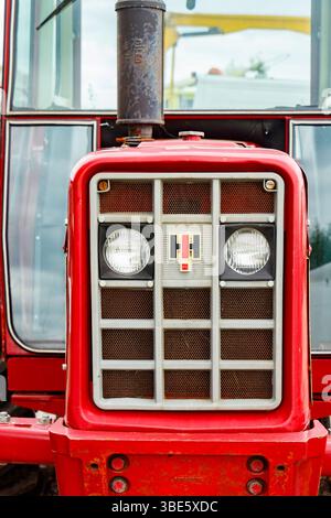 Primo piano di un trattore rosso vintage International Harvester anteriore con luci e calandra, che mostra elementi rustici di design industriale Foto Stock
