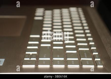 Tastiera color oro di un notebook con sfondo sfocato e luce intensa su una superficie. Foto Stock