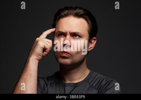 Ritratto di un giovane uomo pensante su sfondo scuro Foto Stock