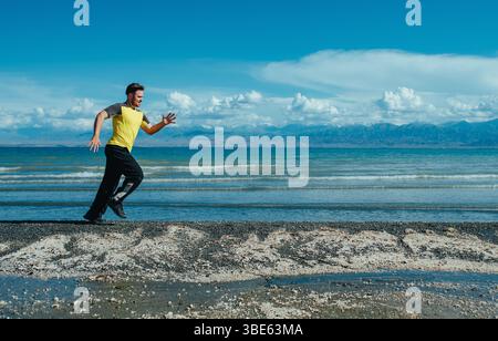 Giovane sportivo che corre sulla riva del lago in estate Foto Stock