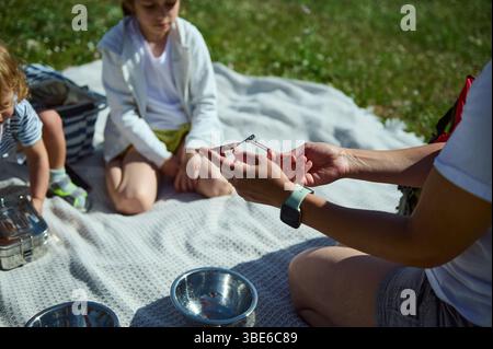 Una famiglia trascorre del tempo all'aperto facendo un picnic su un prato, dimostrando il legame e godendosi la natura in una giornata di sole. I bambini si impegnano giocosamente in questo Foto Stock