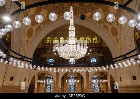 I magnifici interni della grande Moschea al Fateh di Manama presentano lampadari ornati e soffitto ad arco che mostrano lo splendore architettonico islamico. Foto Stock