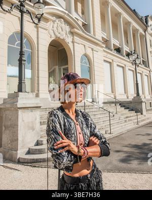 Ritratto di una bella donna in piedi di fronte al casinò di Lucerna, Svizzera. La modella indossa un cappello, occhiali da sole, blazer. Foto Stock