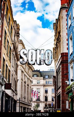 Veduta urbana di Soho a Londra con un segno prominente e Union Jacks sullo sfondo. Foto Stock